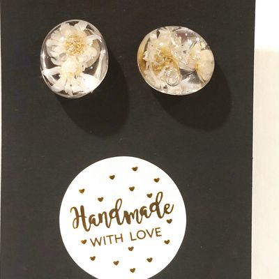 a pair of earrings with white flowers on a black background