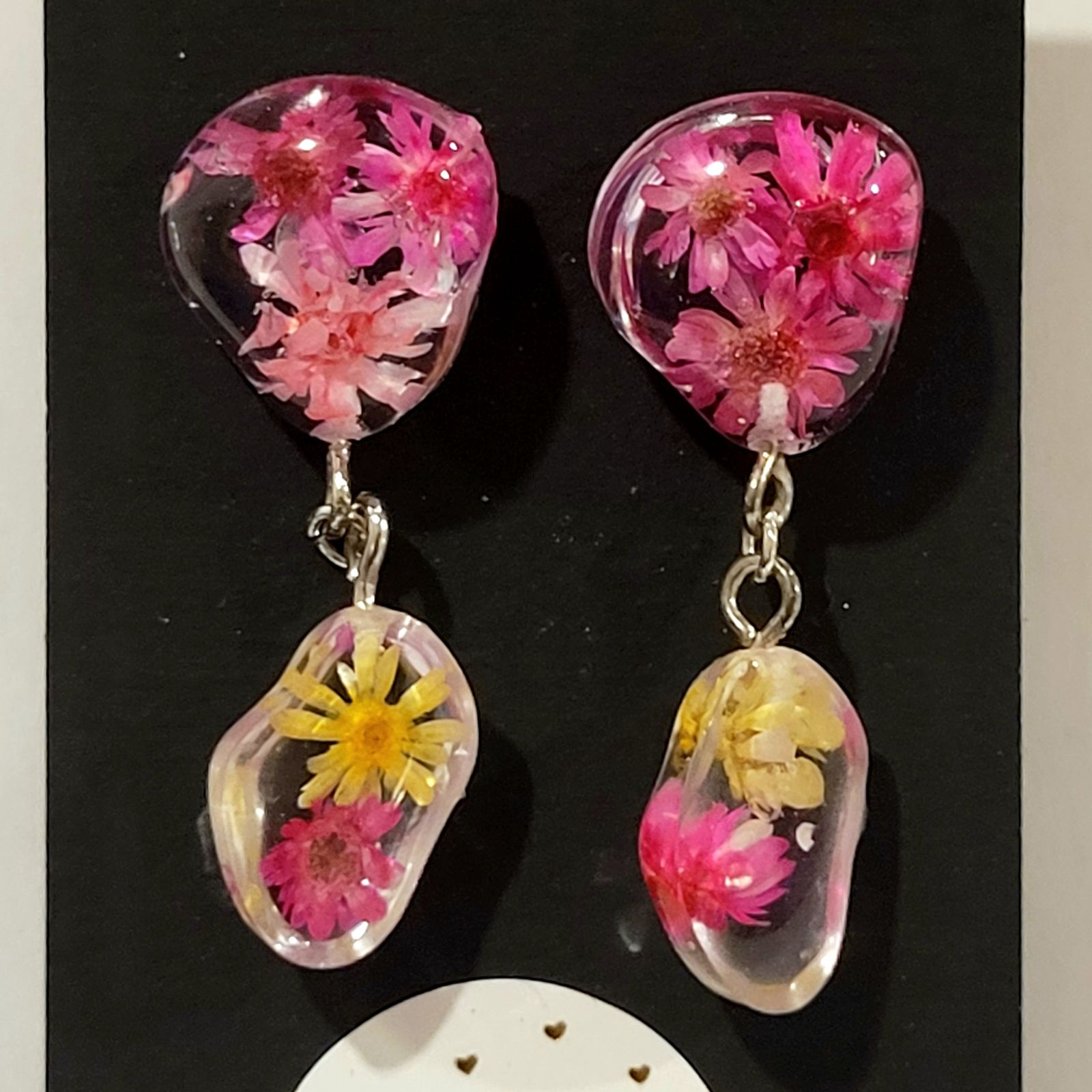 a pair of pink and yellow flowers hanging from a pair of earrings