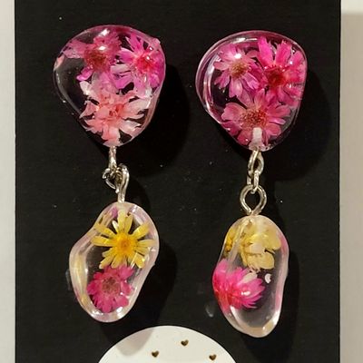a pair of pink and yellow flowers hanging from a pair of earrings
