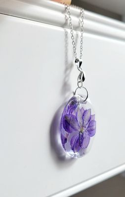 a purple flower in a glass ball on a chain
