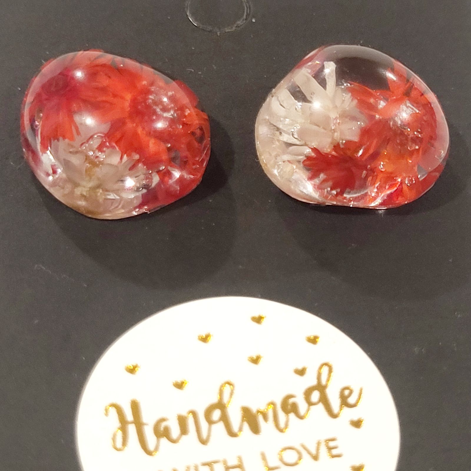 a pair of red and white earrings sitting on top of a table