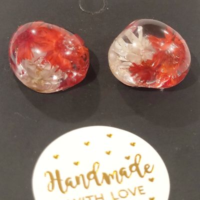 a pair of red and white earrings sitting on top of a table