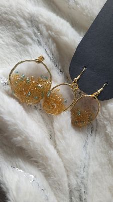 a pair of gold earrings sitting on top of a white blanket