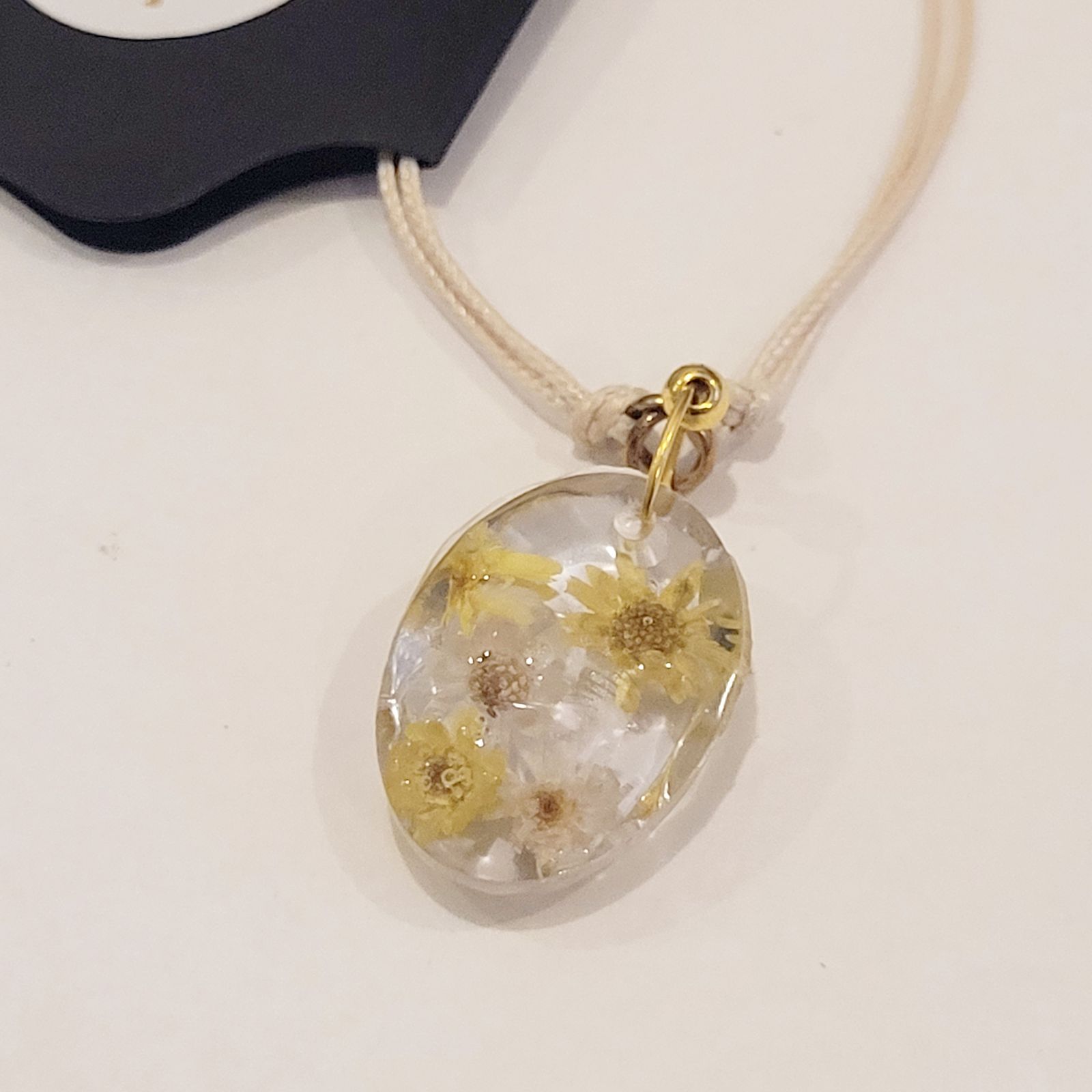 a necklace with a flower pendant on a cord