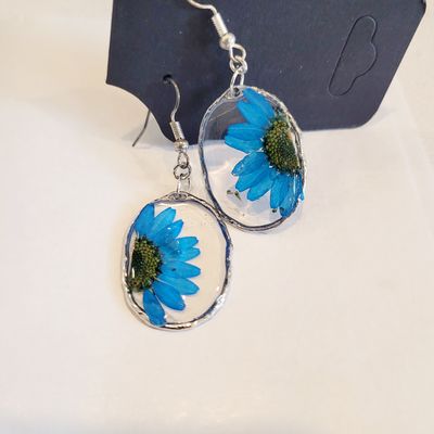 a pair of earrings with a blue flower on them