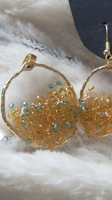a pair of gold hoop earrings with green beads