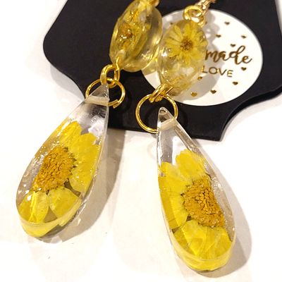 a pair of dandelion earrings sitting on top of a table