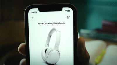 a person holding up a cell phone with headphones on it