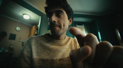 a man in a sweater pointing at the camera