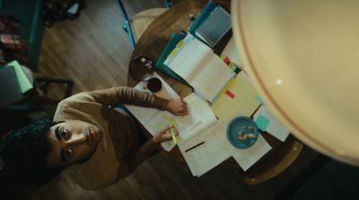 a person sitting at a table with papers and pens