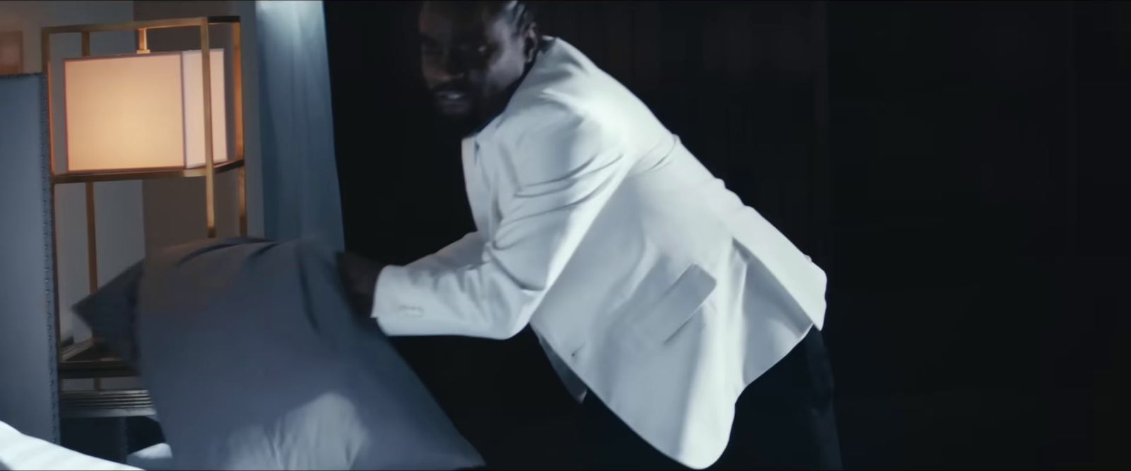 a man in a white shirt leaning against a bed