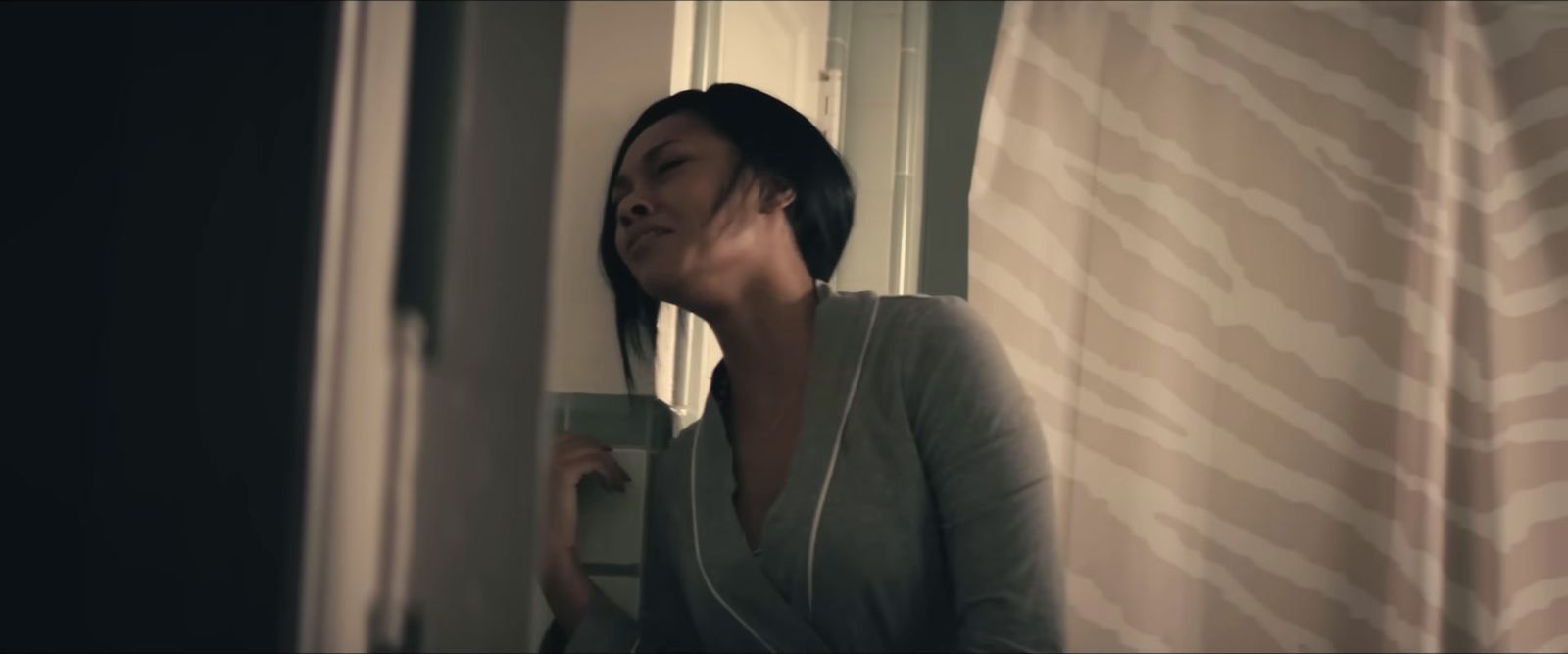 a woman standing next to a window holding a cup