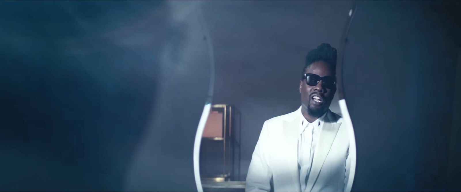 a man in a white suit and sunglasses standing in front of a mirror