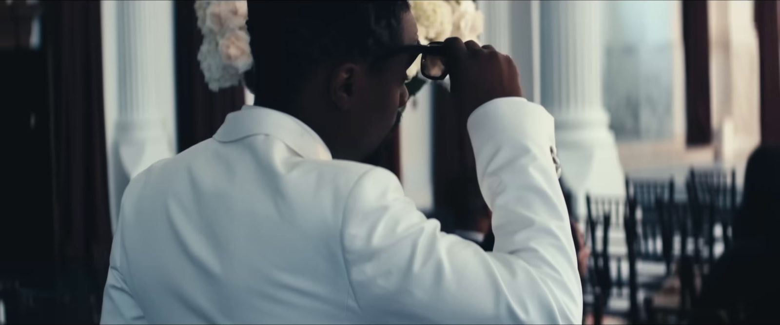 a man in a white shirt and flower in his hair