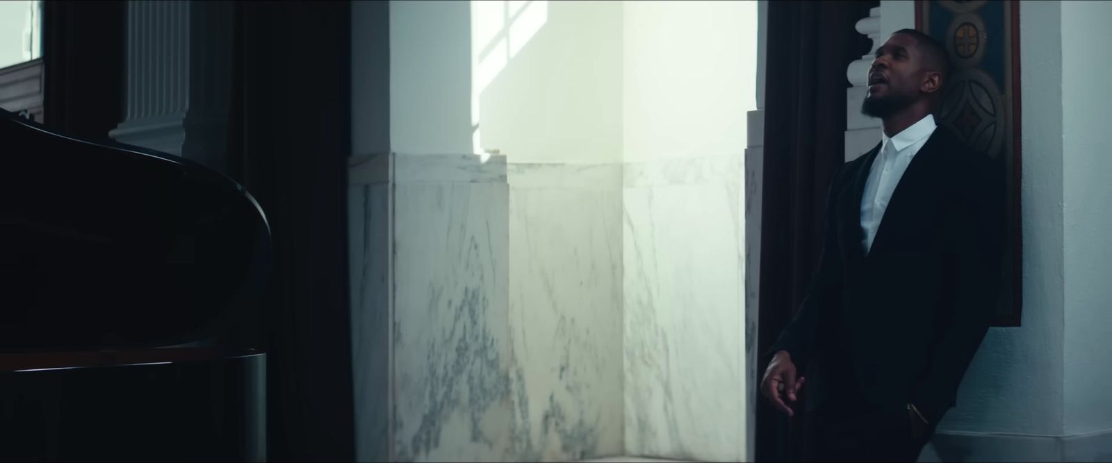 a man in a suit standing next to a piano