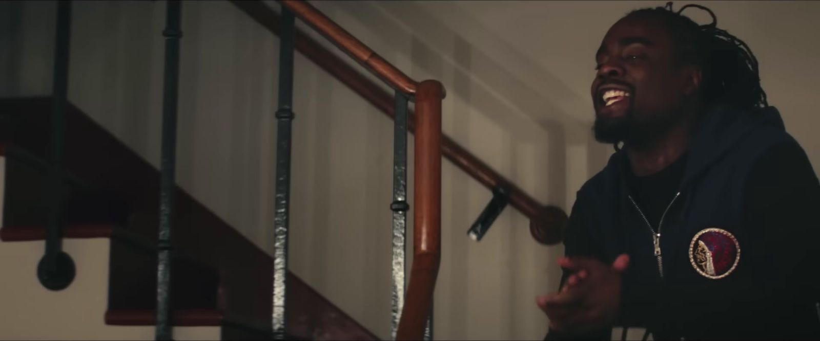 a man with dreadlocks standing in front of a stair case