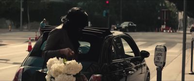 a woman getting out of a car with a bouquet of flowers