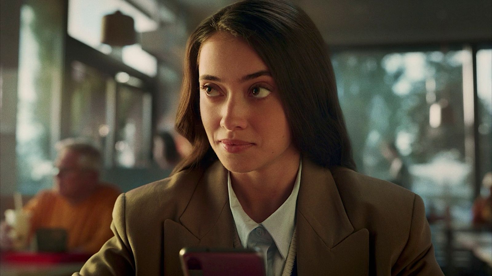 a woman sitting at a table looking at a cell phone