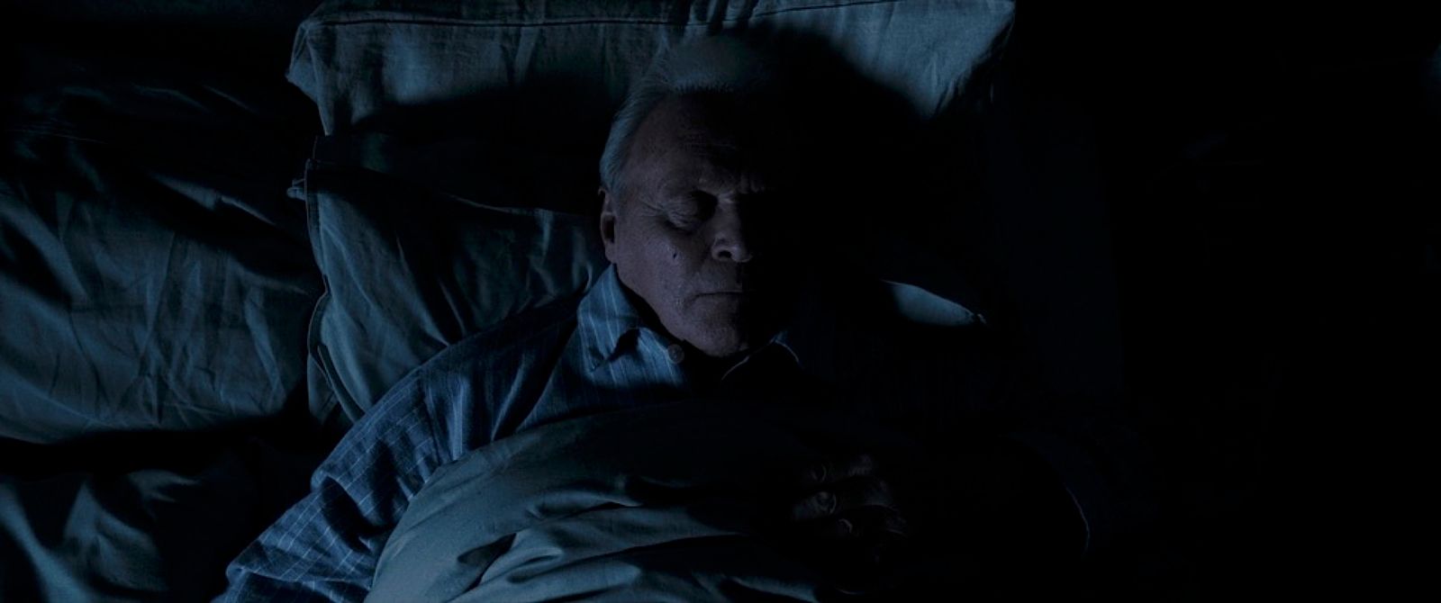 an older man sleeping in a dark room