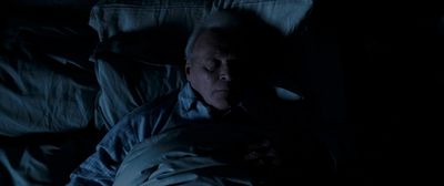 an older man sleeping in a dark room