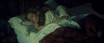 a man and a woman laying in bed in the dark