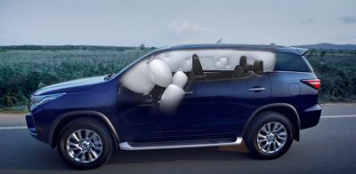 a blue suv driving down a road next to a corn field