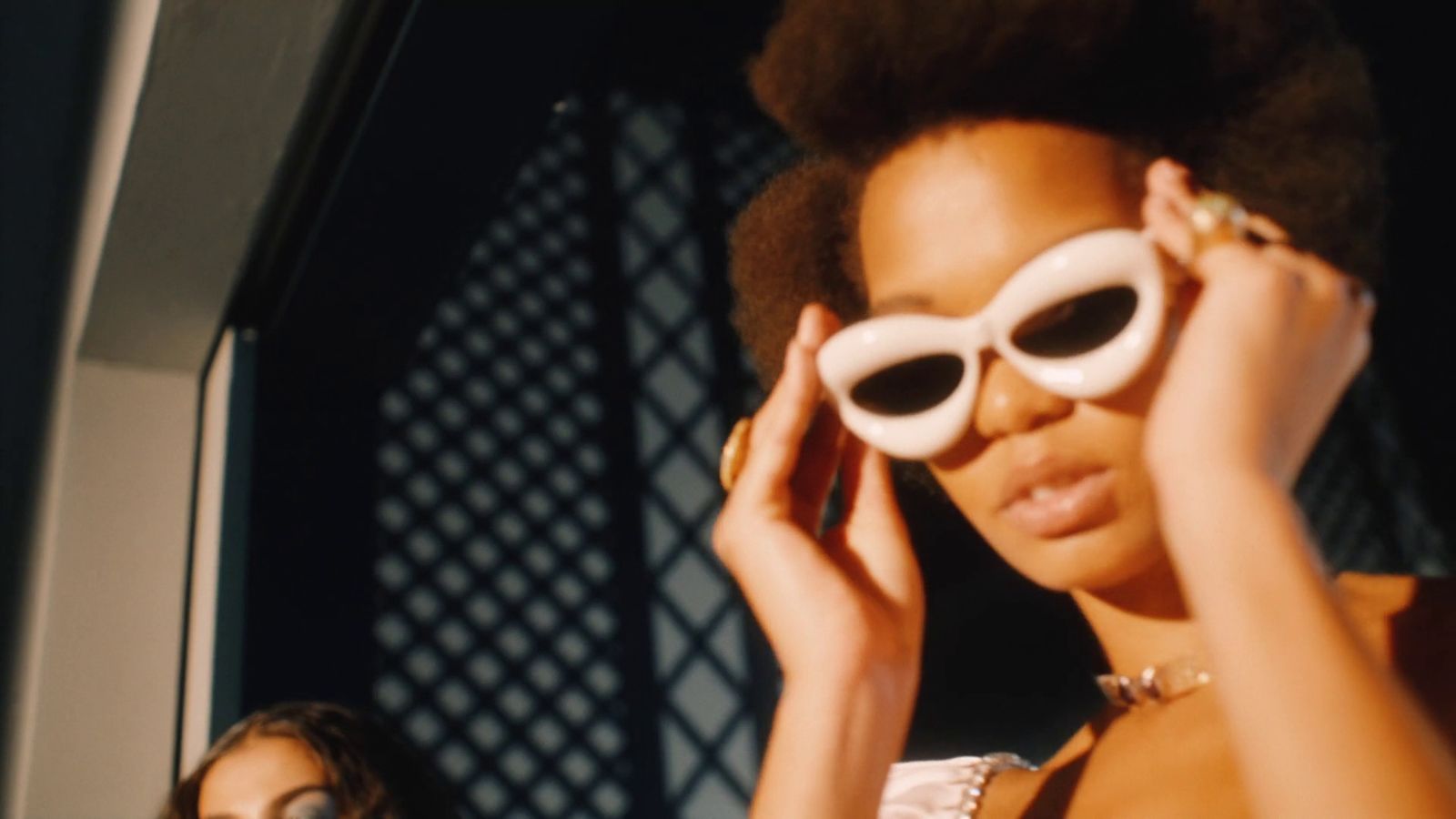 a woman in a white dress holding a pair of white sunglasses