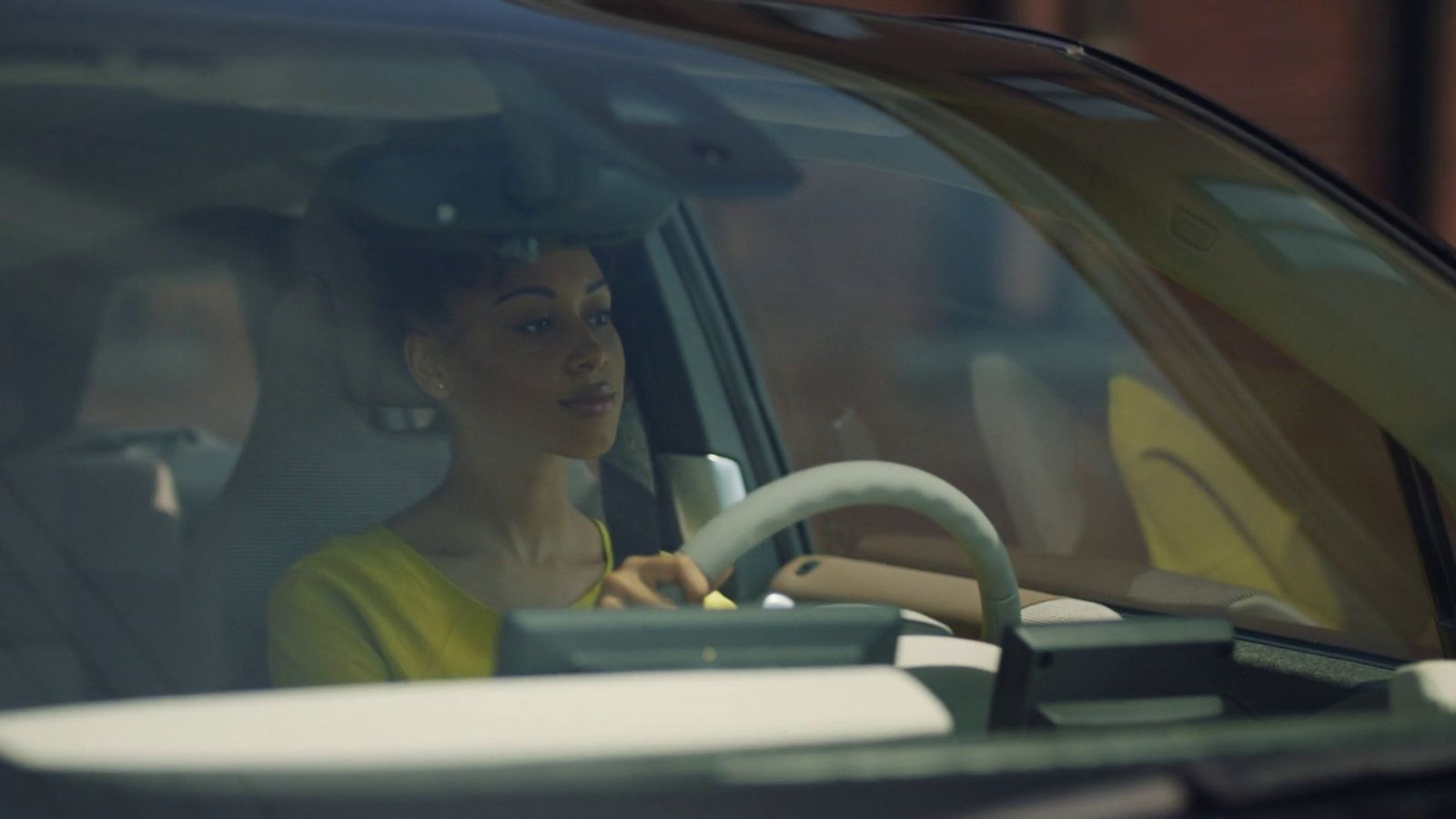 a woman sitting in a car with a steering wheel