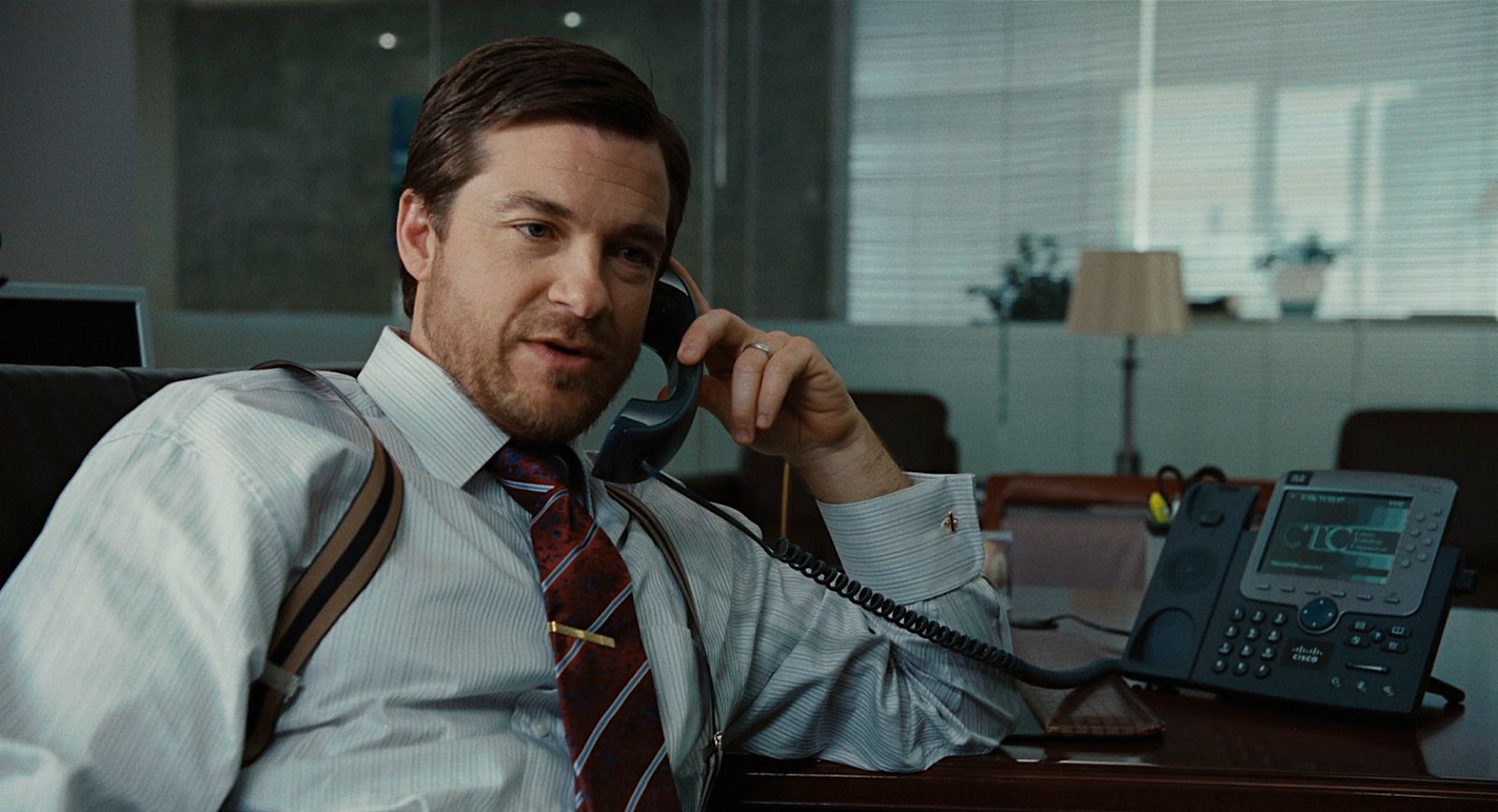 a man sitting at a desk talking on a phone