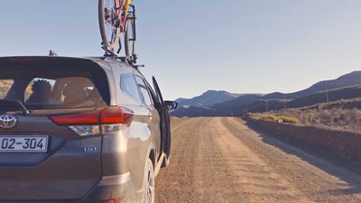 a car parked on a dirt road with a bike on the roof