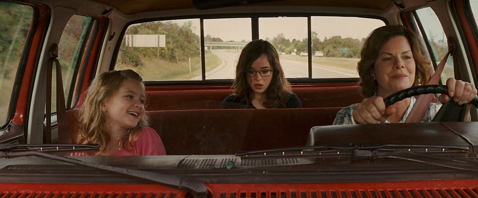 two women and a girl sitting in the back of a truck