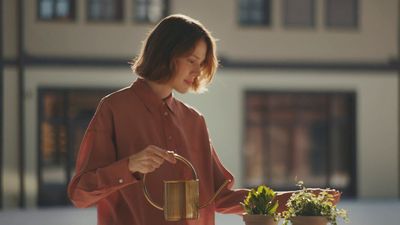 a woman watering flowers with a watering can