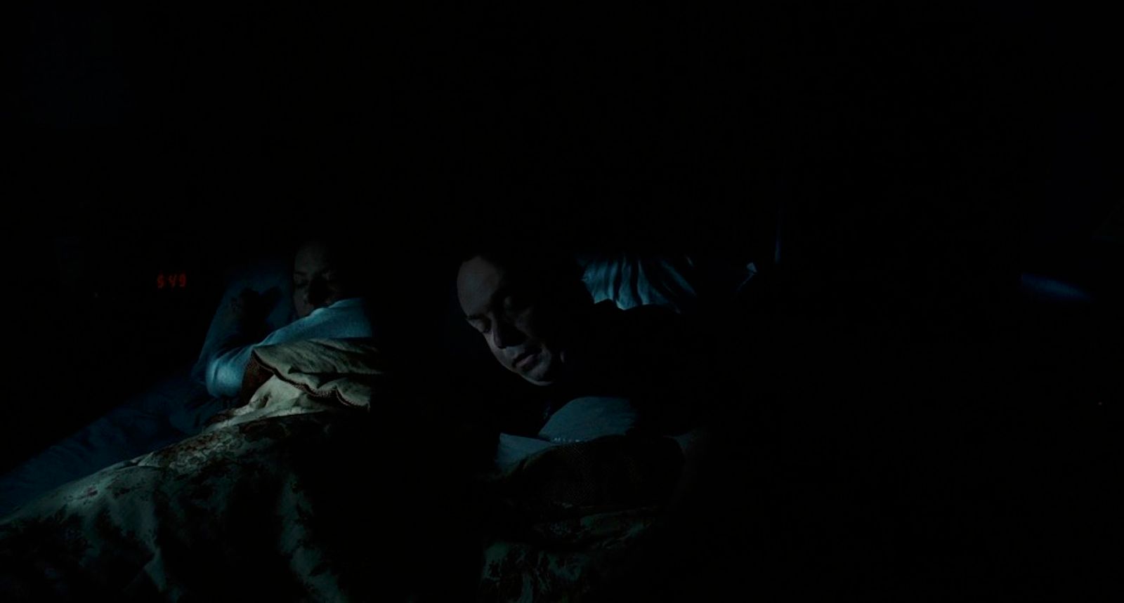 a man laying in bed in the dark