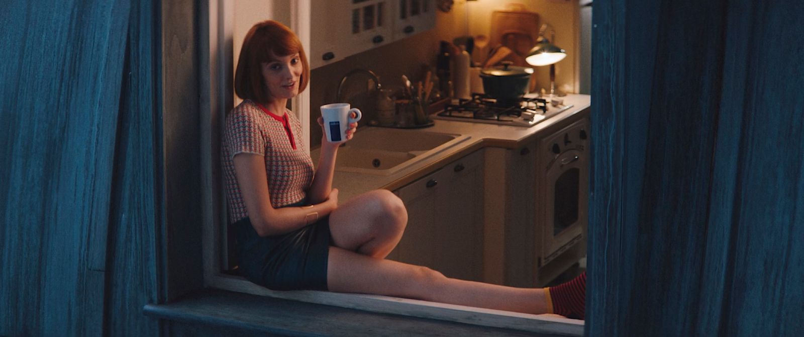 a woman sitting on a window sill holding a cup