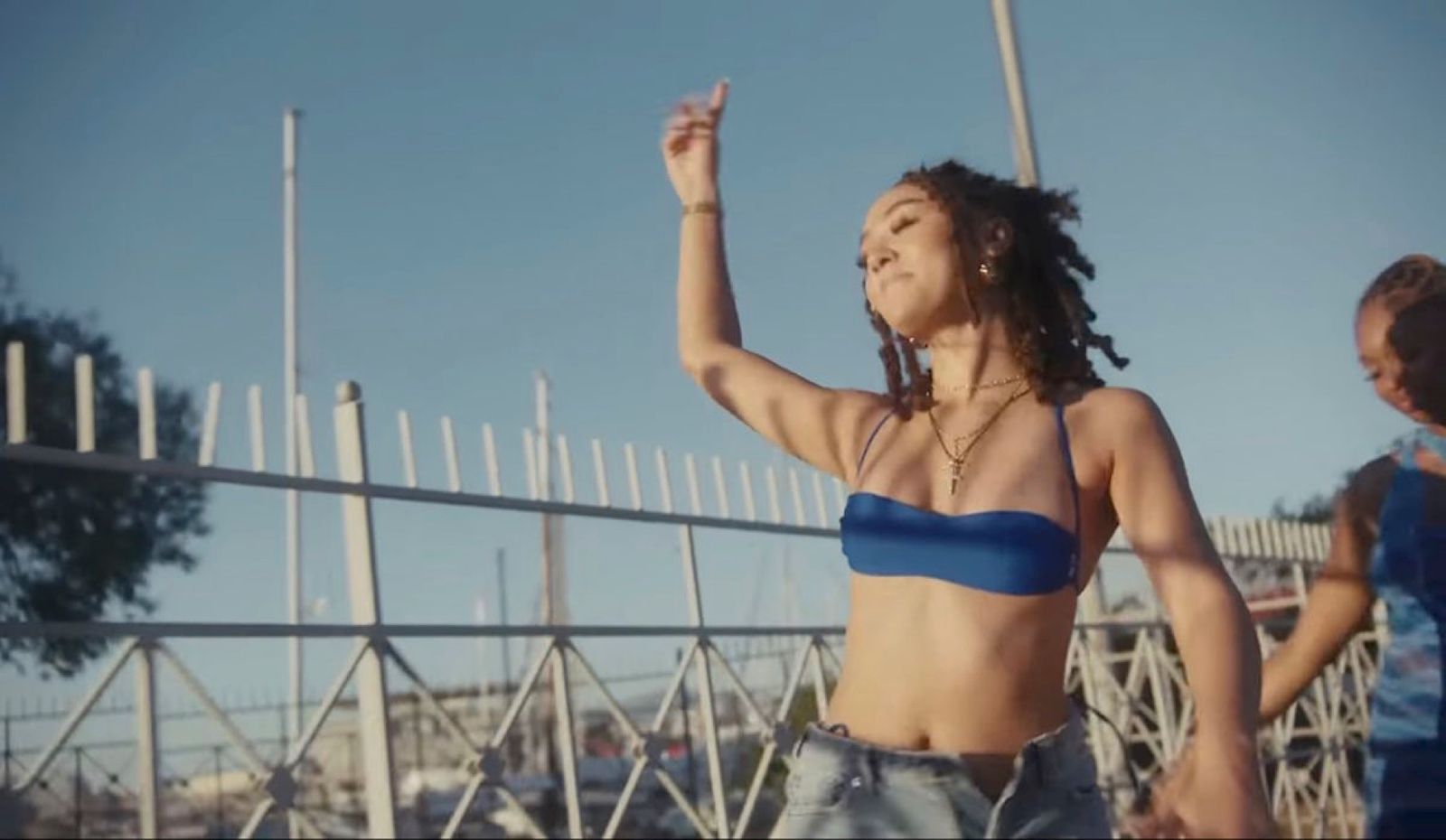 a woman in a blue bikini standing next to a fence