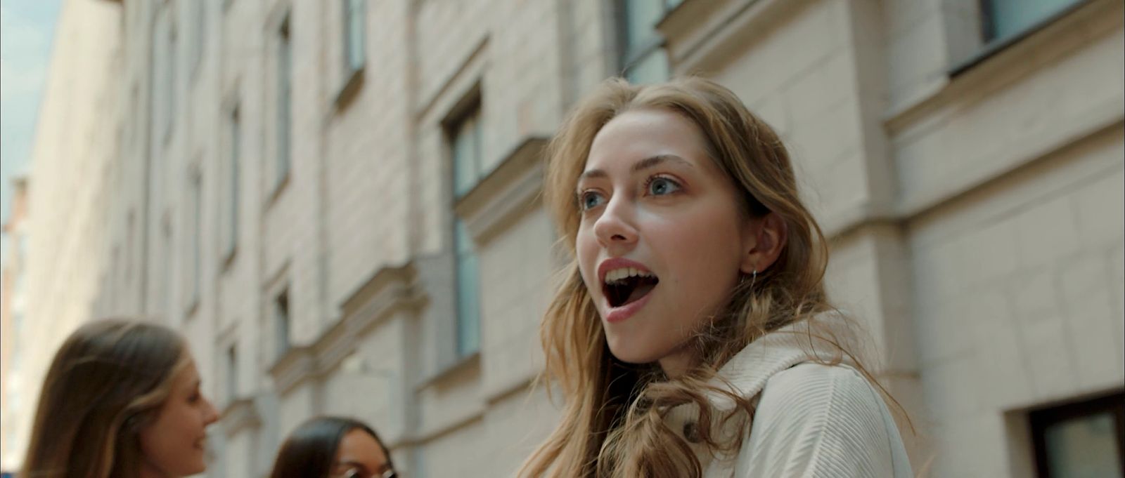 a woman standing next to another woman in front of a building