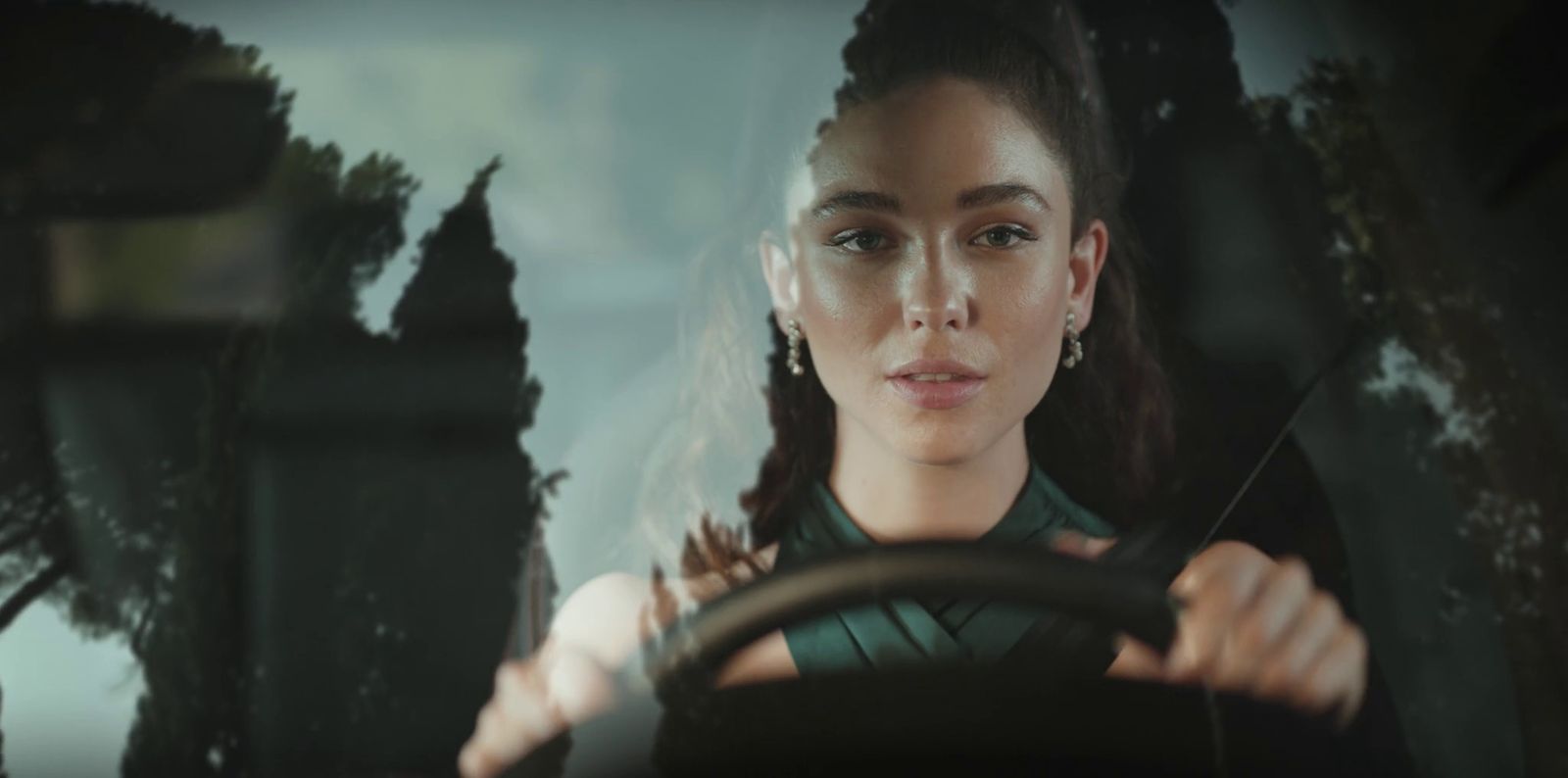 a woman driving a car with trees in the background