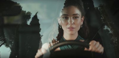 a woman driving a car with trees in the background