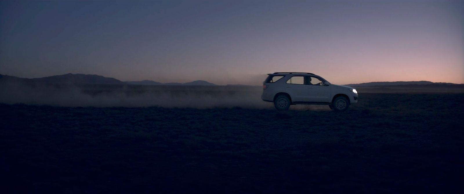 a car driving through a field at night