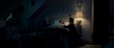 a man and a woman sitting on a bed in a dark room