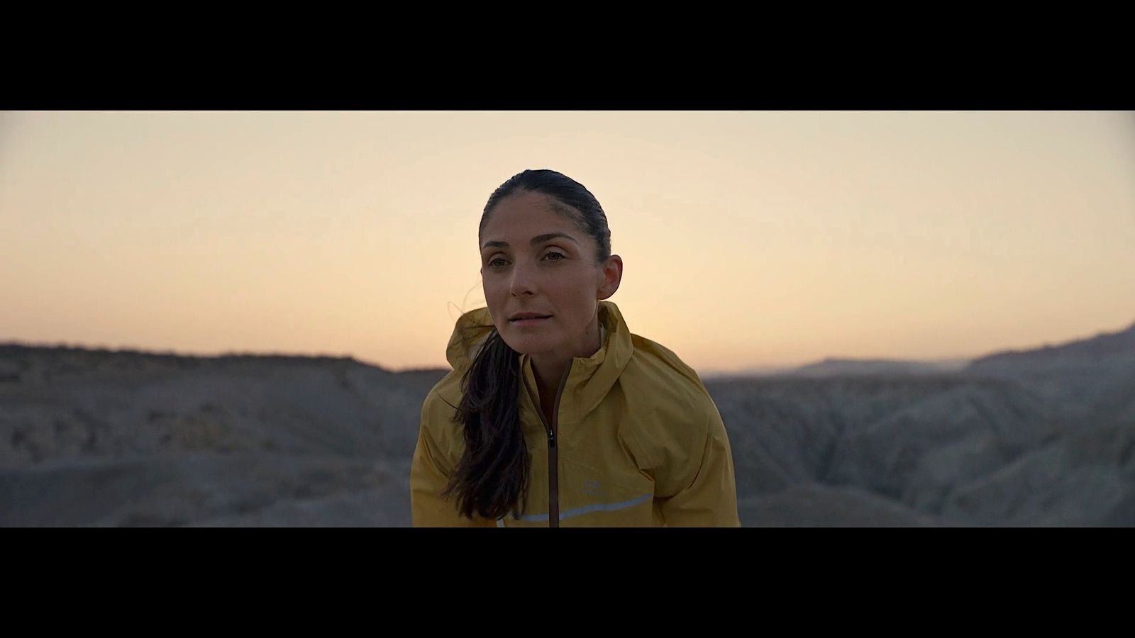 a woman in a yellow jacket standing in the desert