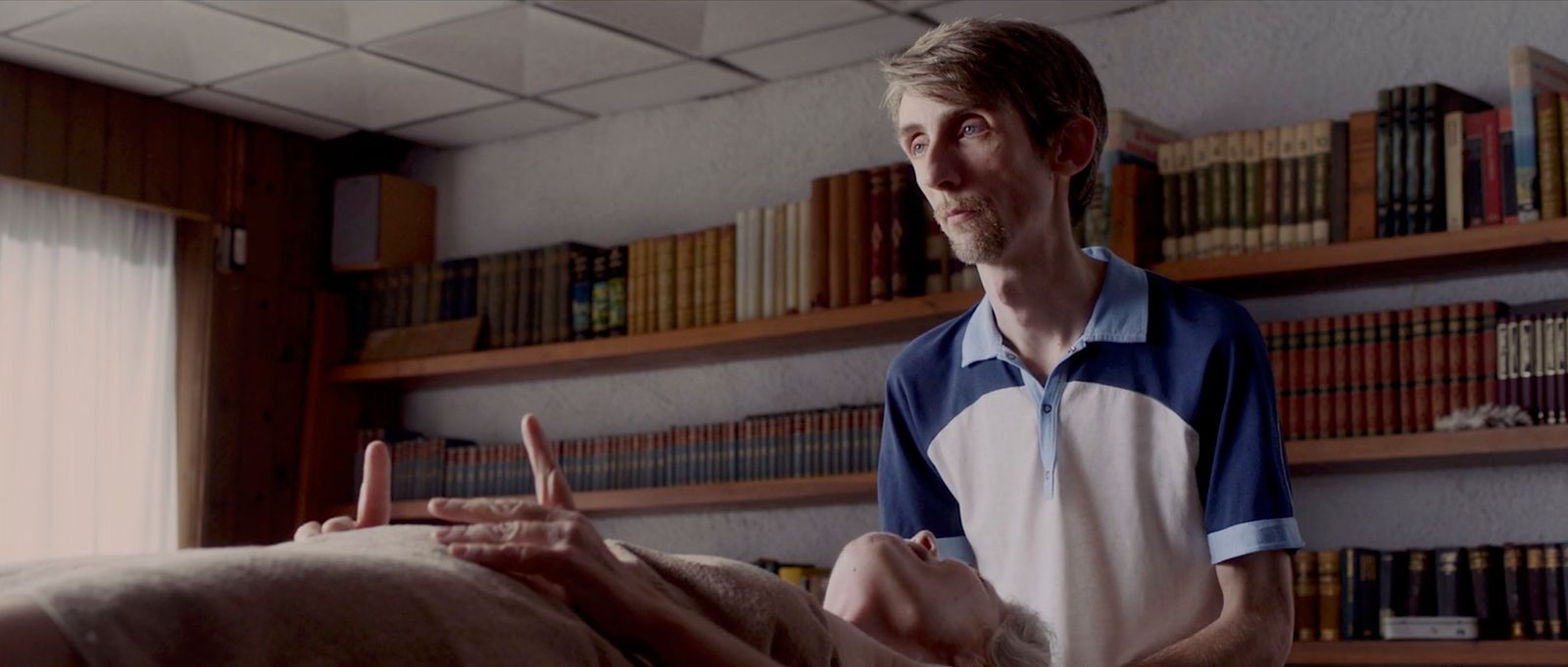 a man standing next to a bed in a room