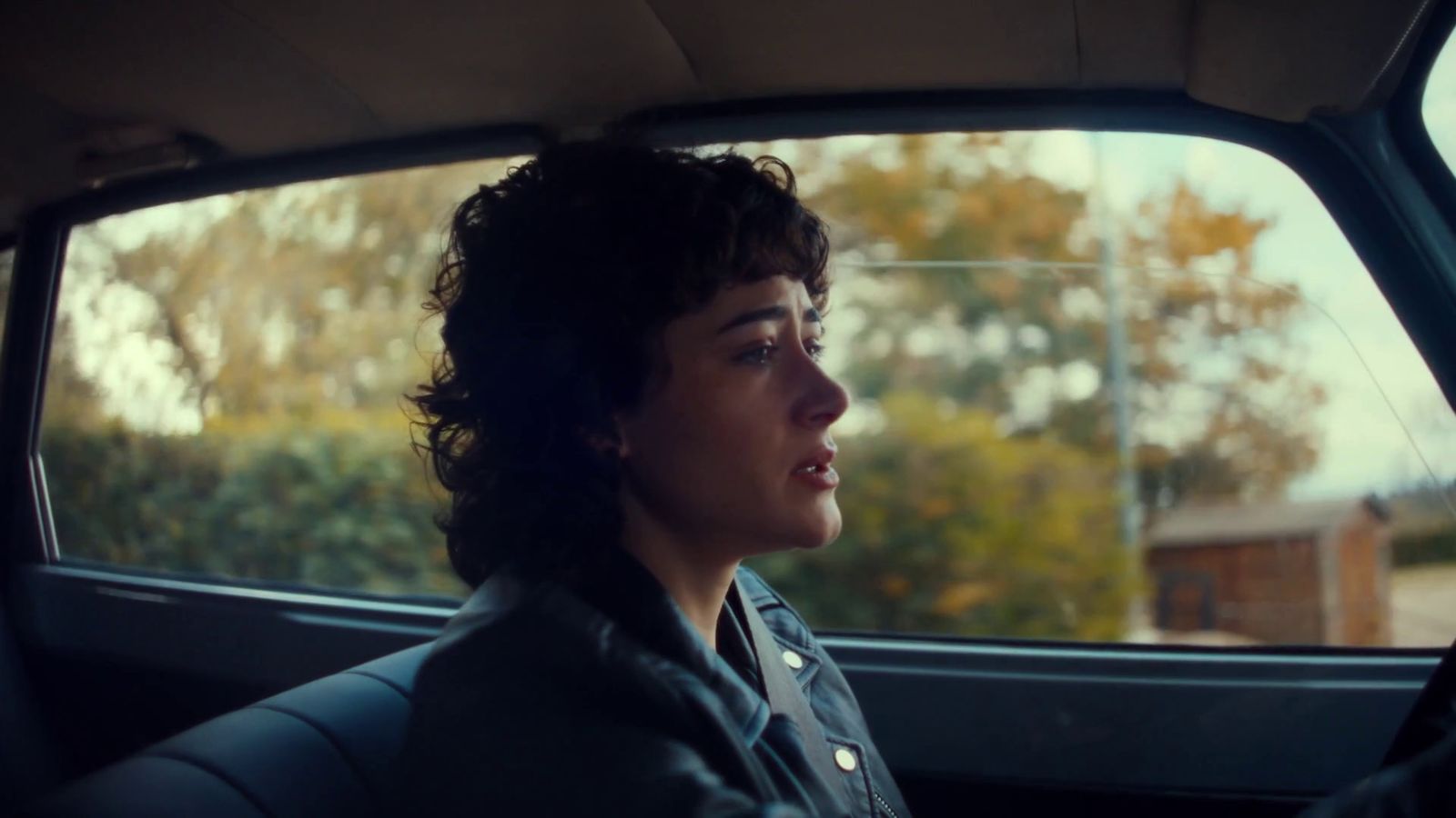 a woman sitting in a car looking out the window