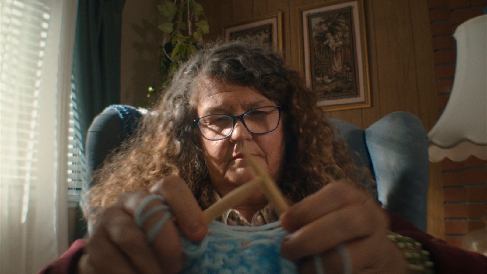 a woman sitting in a chair knitting a sweater