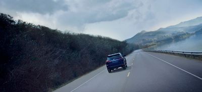 a car driving down a road next to a body of water