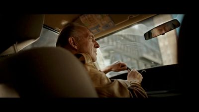 a man sitting in a car with his hand on the steering wheel