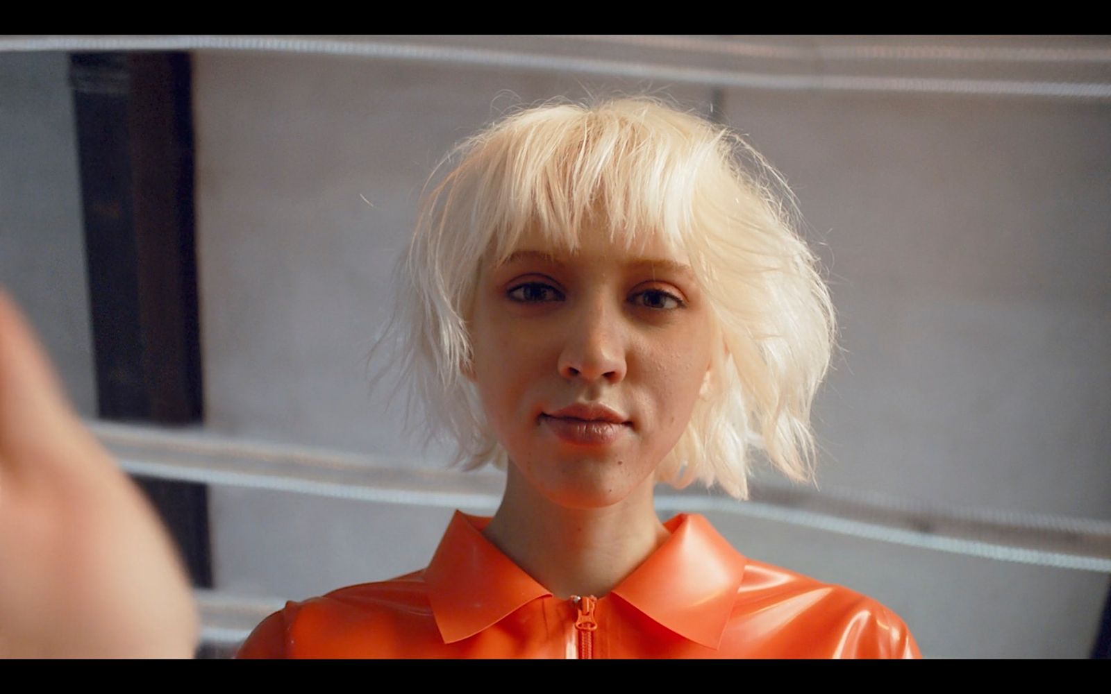 a woman with blonde hair wearing an orange shirt