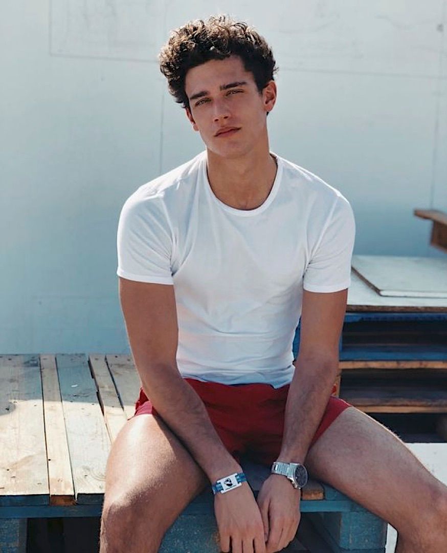 a young man sitting on top of a wooden bench