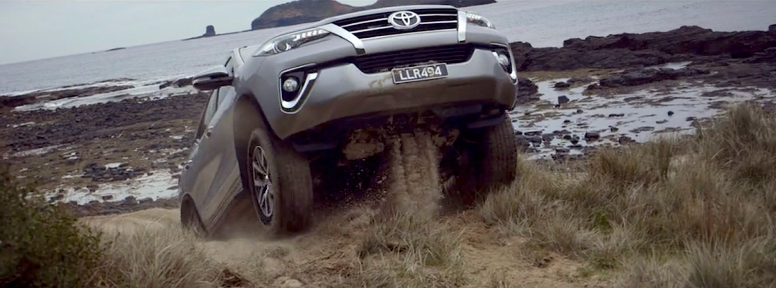 a grey toyota suv driving on a dirt road