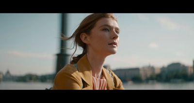 a woman sitting on a bench near a body of water